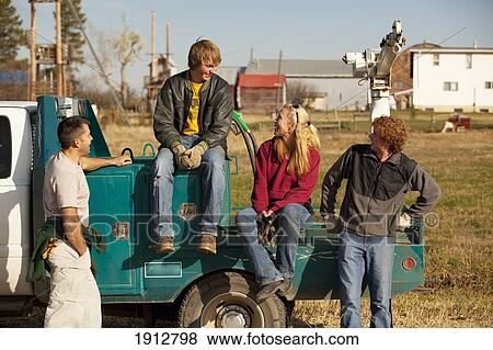 a group of people talking while they sit on the back of a truck; three hills, alberta, canada View Large Photo Image Stock Photo - a group of people talking while they sit on the back of a truck; three hills, alberta, canada. Fotosearch