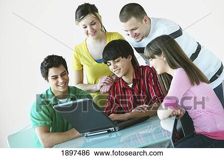 Stock Photograph - a group of teenagers gathered around a laptop computer. Fotosearch