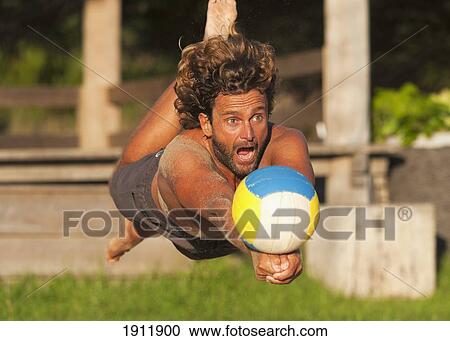 Stock Image - a man diving for a beach ball; tarifa, cadiz, andalusia, spain. Fotosearch