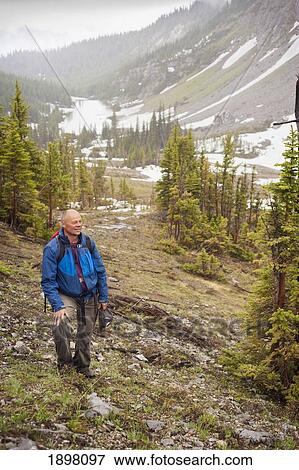 Stock Photo - a man hiking through the mountains; fernie, british columbia, canada. Fotosearch