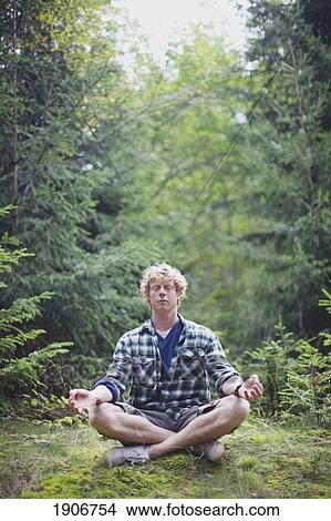 Picture - a man meditating in the forest; france. Fotosearch
