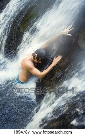 Stock Photo - a man standing under a waterfall at the currumbin rock pools in currumbin valley; gold coast, queensland, australia. Fotosearch