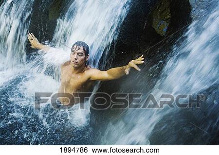 a man standing under a waterfall with arms outstretched at the currumbin rock pools in currumbin valley; gold coast, queensland, australia View Large Photo Image Stock Photograph - a man standing under a waterfall with arms outstretched at the currumbin rock pools in currumbin valley; gold coast, queensland, australia. Fotosearch