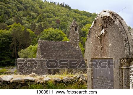 Stock Image - a monastery and a tombstone in a cemetery; glendalough, county wicklow, ireland. Fotosearch