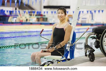 Picture - a paraplegic woman enters a swimming pool on a lift; edmonton, alberta, canada. Fotosearch