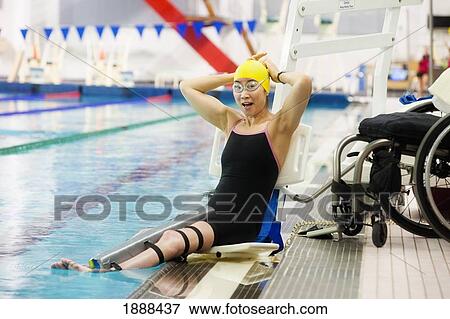 a paraplegic woman sits at the edge of a swimming pool on a lift beside her wheelchair and prepares to swim; edmonton, alberta, canada View Large Photo Image Stock Photo - a paraplegic woman sits at the edge of a swimming pool on a lift beside her wheelchair and prepares to swim; edmonton, alberta, canada. Fotosearch