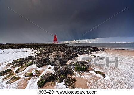 a red lighthouse along the coast under a stormy sky; south shields, tyne and wear, england View Large Photo Image Stock Photo - a red lighthouse along the coast under a stormy sky; south shields, tyne and wear, england. Fotosearch
