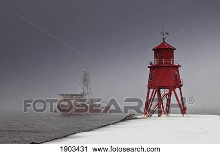 a red lighthouse on the shore in winter with a boat out in the water; south shields, tyne and wear, england View Large Photo Image Stock Image - a red lighthouse on the shore in winter with a boat out in the water; south shields, tyne and wear, england. Fotosearch