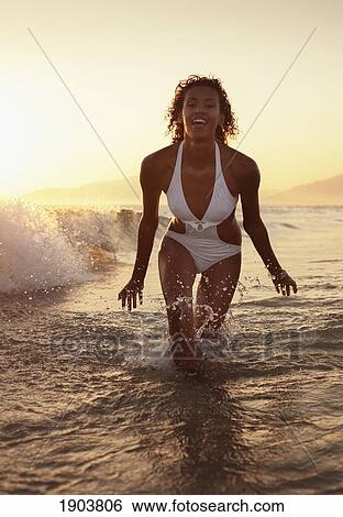 a woman in a bathing suit splashes in the ocean at sunset off los lances beach; tarifa, cadiz, andalusia, spain View Large Photo Image Stock Photograph - a woman in a bathing suit splashes in the ocean at sunset off los lances beach; tarifa, cadiz, andalusia, spain. Fotosearch