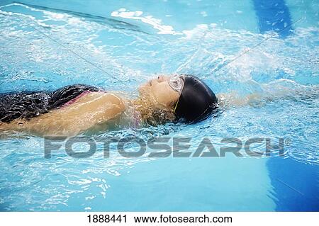 Stock Image - a woman wearing a cap and goggles swims the back stroke; edmonton, alberta, canada. Fotosearch