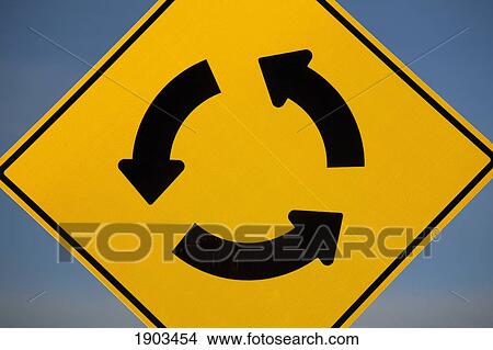 a yellow traffic sign with three arrows in a circle against a blue sky; calgary, alberta, canada View Large Photo Image Picture - a yellow traffic sign with three arrows in a circle against a blue sky; calgary, alberta, canada. Fotosearch