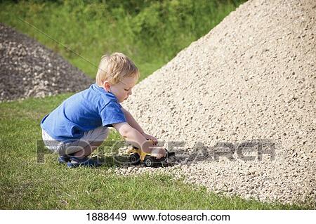 a young boy drives his toy truck through a rock pile; edmonton, alberta, canada View Large Photo Image Stock Photo - a young boy drives his toy truck through a rock pile; edmonton, alberta, canada. Fotosearch