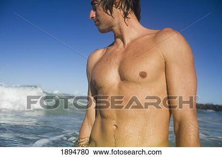 a young man standing in water watching the waves; gold coast, queensland, australia View Large Photo Image Stock Image - a young man standing in water watching the waves; gold coast, queensland, australia. Fotosearch