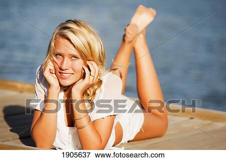 a young woman basks in the sun by the water; currumbin, gold coast, queensland, australia View Large Photo Image Stock Photo - a young woman basks in the sun by the water; currumbin, gold coast, queensland, australia. Fotosearch