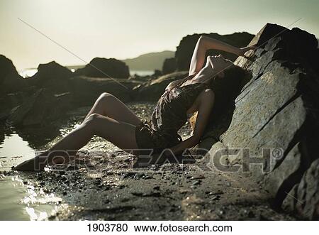 Stock Image - a young woman poses on the beach at sunset; tarifa, cadiz, andalusia, spain. Fotosearch
