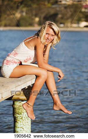 Stock Image - a young woman sits on the edge of a dock; currumbin, gold coast, queensland, australia. Fotosearch