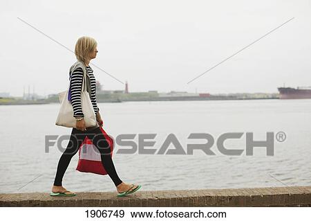 a young woman walking on the wall by the harbor; houten, the netherlands View Large Photo Image Stock Photo - a young woman walking on the wall by the harbor; houten, the netherlands. Fotosearch