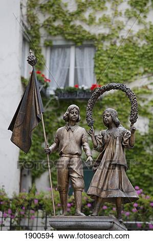 Picture - bronze statues of a boy and girl with an ivy covered building and flowers in the background; lindau, germany. Fotosearch