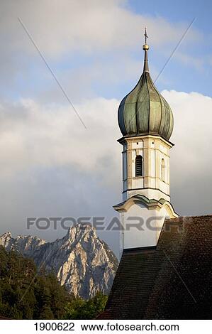Stock Image - church bell tower with a mountain peak in the background; fussen, germany. Fotosearch