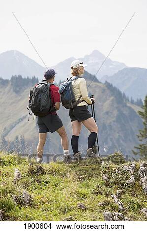 female and male hikers on a grassy viewpoint overlooking a mountain valley and range; oberstdorf, germany View Large Photo Image Picture - female and male hikers on a grassy viewpoint overlooking a mountain valley and range; oberstdorf, germany. Fotosearch