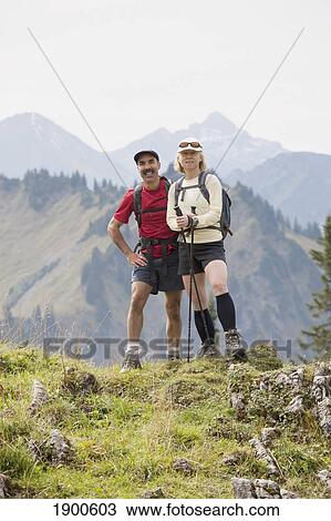 female and male hikers on a grassy viewpoint with a mountain valley and range in the background; oberstdorf, germany View Large Photo Image Stock Image - female and male hikers on a grassy viewpoint with a mountain valley and range in the background; oberstdorf, germany. Fotosearch