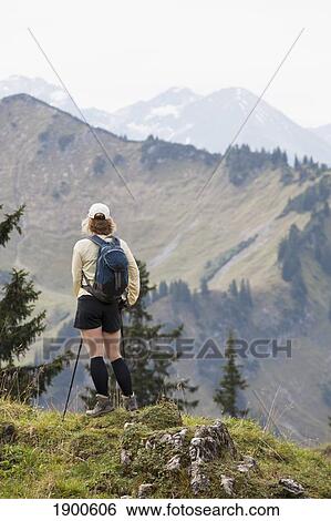 female hiker on a grassy viewpoint overlooking a mountain valley and range; oberstdorf, germany View Large Photo Image Stock Photograph - female hiker on a grassy viewpoint overlooking a mountain valley and range; oberstdorf, germany. Fotosearch