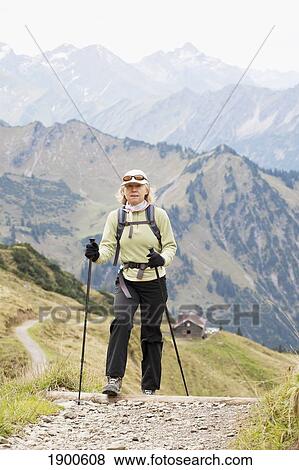 female hiker on a path with an alpine hut and mountain ranges in the background; oberstdorf, germany View Large Photo Image Stock Photo - female hiker on a path with an alpine hut and mountain ranges in the background; oberstdorf, germany. Fotosearch