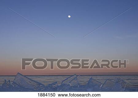 Stock Image - full moon at dusk with ice on lake superior; grand portage, minnesota, united states of america. Fotosearch