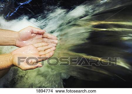 Picture - hands held out to catch water at the currumbin rock pools in the currumbin valley; gold coast, queensland, australia. Fotosearch