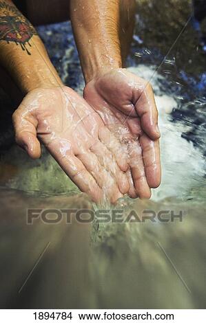 Picture - hands touch the cascade of water at currumbin rock pools in currumbin valley; gold coast, queensland, australia. Fotosearch