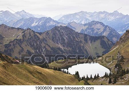 high angle view of a mountain lake and alpine hut with several mountain ranges in the background; oberstdorf, germany View Large Photo Image Stock Photo - high angle view of a mountain lake and alpine hut with several mountain ranges in the background; oberstdorf, germany. Fotosearch