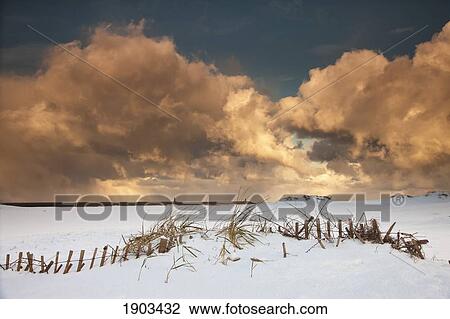 Stock Image - illuminated clouds glowing above a snowy field; south shields, tyne and wear, england. Fotosearch