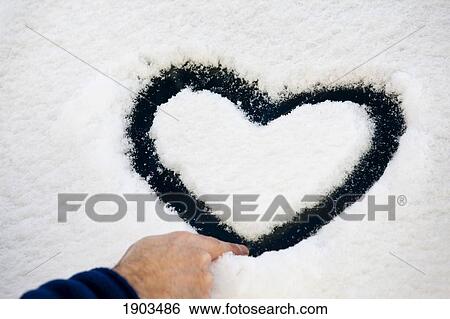Stock Photograph - male hand creating a heart shape in snow on the windshield of a vehicle; calgary, alberta, canada. Fotosearch