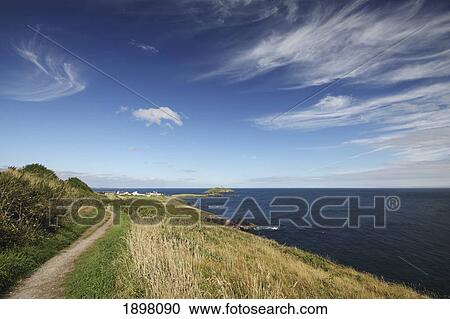Stock Image - path along a cliff and a lighthouse in east cork in munster region; ballycotton, county cork, ireland. Fotosearch