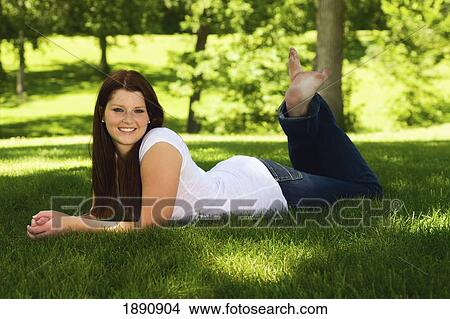 Picture - portrait of a young woman laying on the grass; wilmar, minnesota, united states of america. Fotosearch