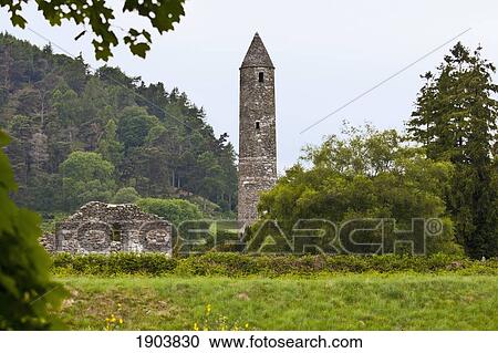 Stock Image - ruins of a building and a round tower on a 6th century monastic site; glendalough, county wicklow, ireland. Fotosearch