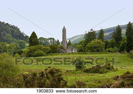 Stock Image - ruins of a building and a round tower on a 6th century monastic site; glendalough, county wicklow, ireland. Fotosearch
