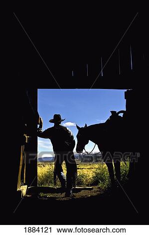 silhouette of a cowboy holding his horse's reins and looks out of the barn as he contemplates the day; seneca, oregon, united states of america View Large Photo Image Stock Image - silhouette of a cowboy holding his horse's reins and looks out of the barn as he contemplates the day; seneca, oregon, united states of america. Fotosearch