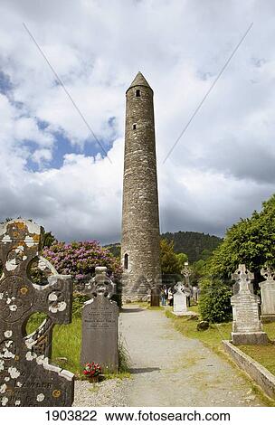 Stock Image - tombstones in a cemetery and a round tower on a 6th century monastic site; glendalough, county wicklow, ireland. Fotosearch