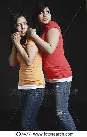 two girls huddling close together looking very afraid View Large Photo Image Stock Photo - two girls huddling close together looking very afraid. Fotosearch