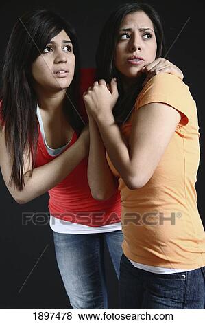 two girls huddling close together looking very afraid View Large Photo Image Stock Photo - two girls huddling close together looking very afraid. Fotosearch