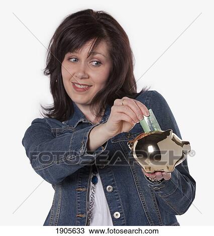 Stock Image - woman saving money in a piggy bank; edmonton, alberta, canada. Fotosearch