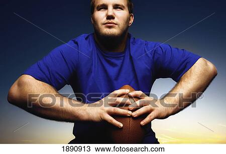 Stock Image - young man holding a football; wilmar, minnesota, united states of america. Fotosearch