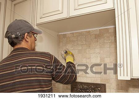 a man installing a travertine mosiac installation on backsplash; st. albert, alberta, canada View Large Photo Image Stock Image - a man installing a travertine mosiac installation on backsplash; st. albert, alberta, canada. Fotosearch