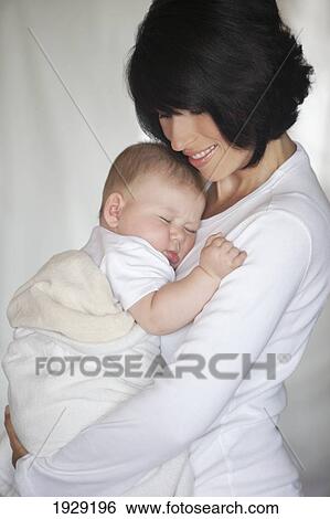 Stock Photograph - a mother holding her sleeping baby. Fotosearch