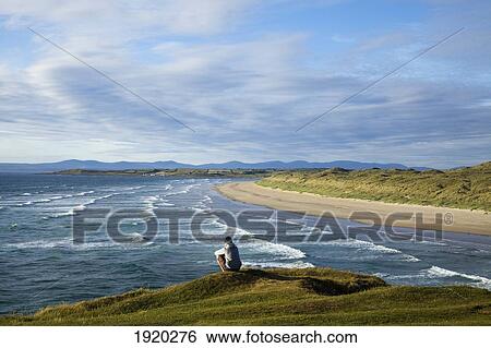 A Person Sitting At The Water'S Edge At The Beach Near Bundora; County Donegal, Ireland View Large Photo Image Stock Photograph - A Person Sitting At The Water'S Edge At The Beach Near Bundora; County Donegal, Ireland. Fotosearch