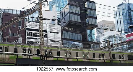 Stock Photo - a public transportation train traveling past buildings in an urban area; tokyo, japan. Fotosearch