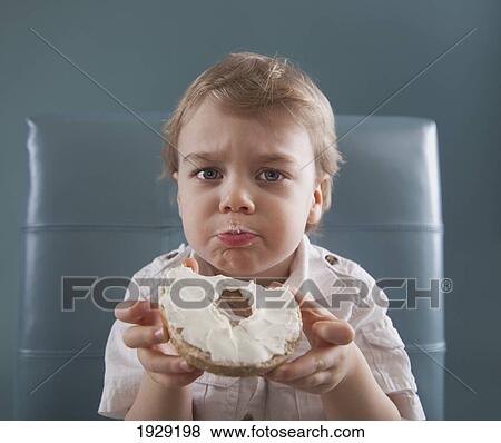 Stock Photo - a toddler eating a bagel with cream cheese. Fotosearch