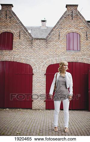 Stock Photography - a woman standing outside a traditional dutch home; houten, the netherlands. Fotosearch