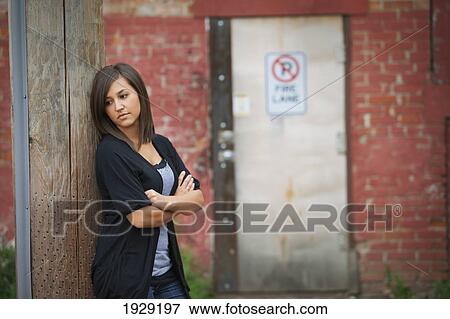Stock Photo - a young woman stands alone in an alley. Fotosearch